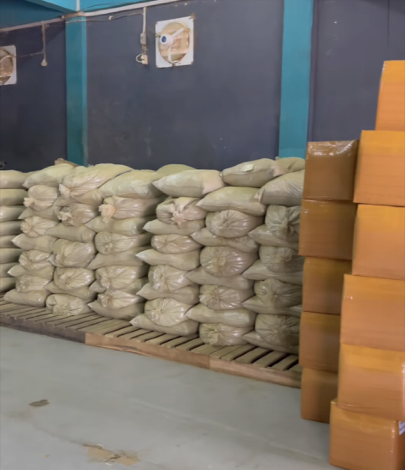 Bulk kratom imports before retail packaging, stacked sacks and boxes in a warehouse